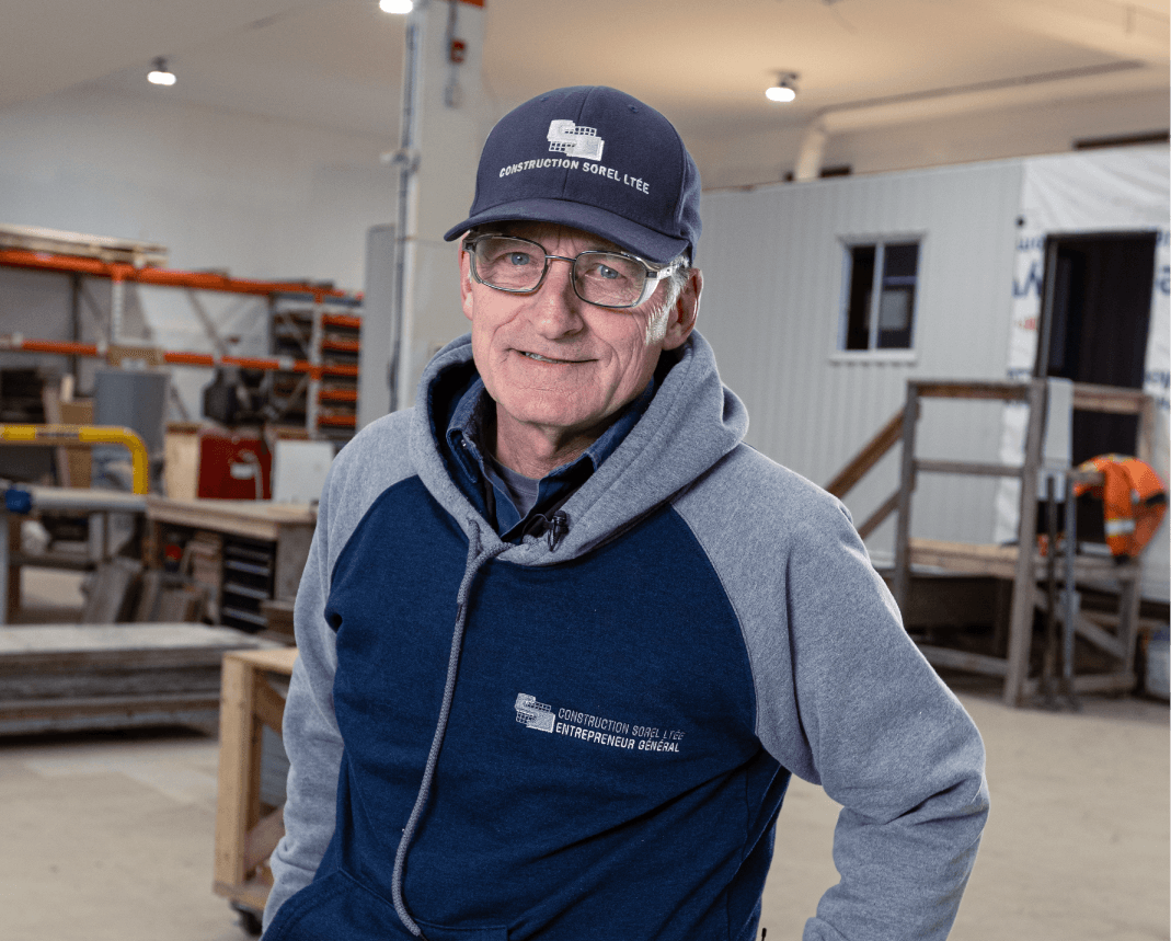 Portrait d'un membre expérimenté de l'équipe Construction Sorel Ltée dans l'atelier, portant la casquette officielle de l'entreprise.