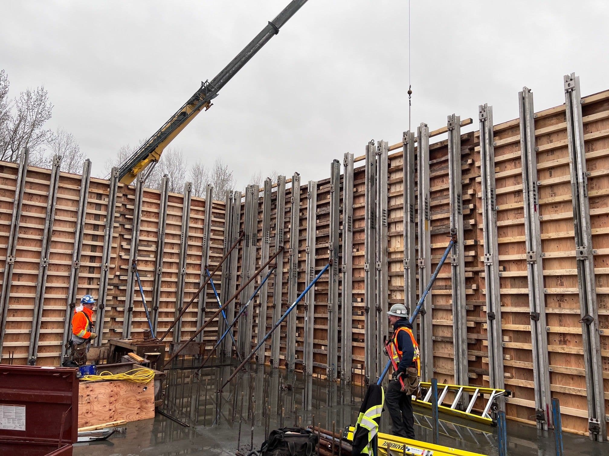 Chantier CSL Ltée : assemblage de coffrages verticaux de grande hauteur pour murs de béton armé, assisté par une grue mobile